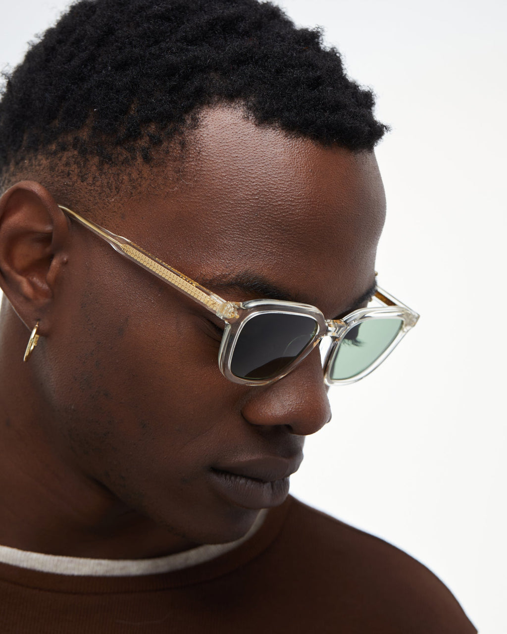 Person wearing gold-framed sunglasses with a neutral background
